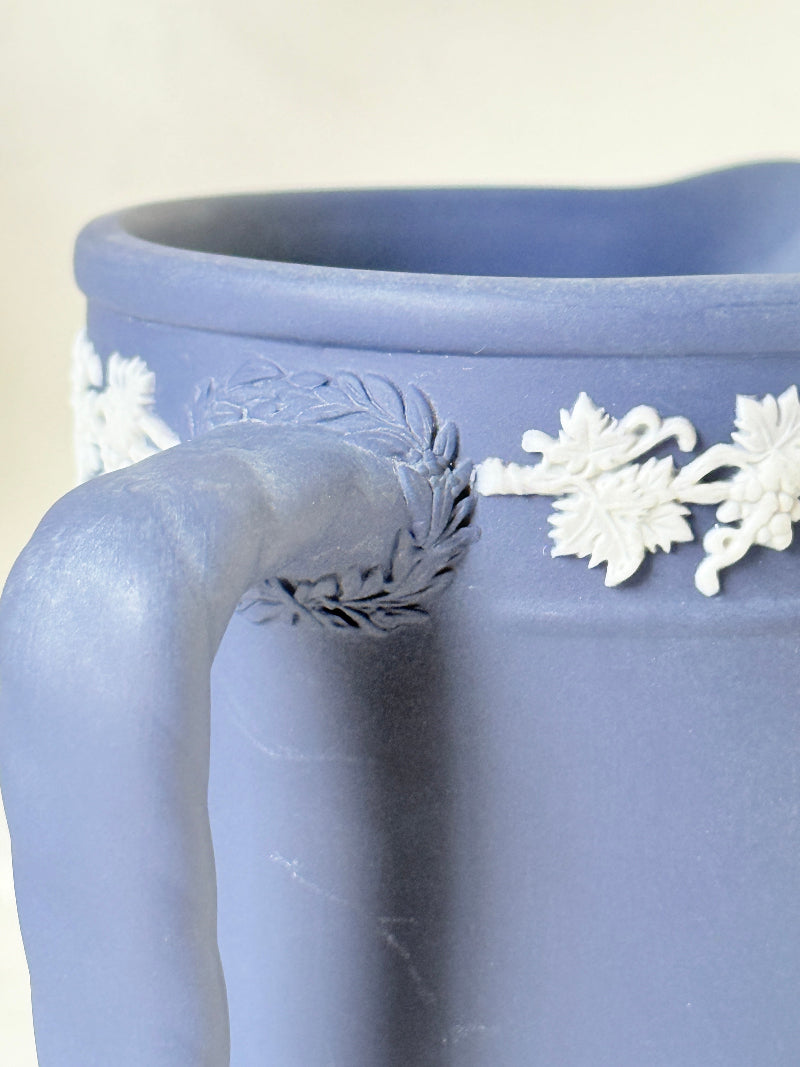 Vintage Wedgwood Portland blue Jasperware jug decorated with white neoclassical figures and a grapevine border, styled with dried stems.