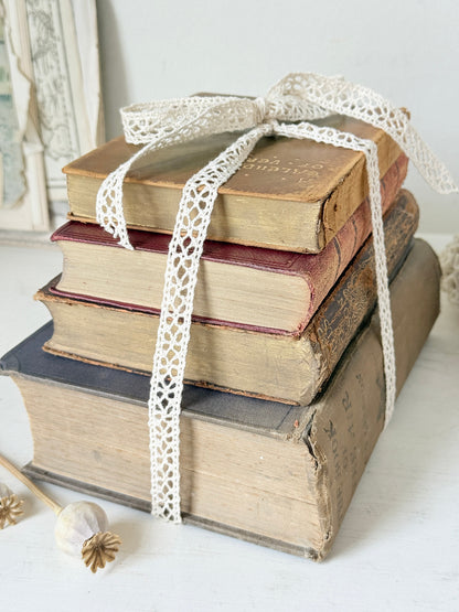 Antique decorative book bundle with faded hardback covers, aged pages and neutral lace tie for vintage interior styling