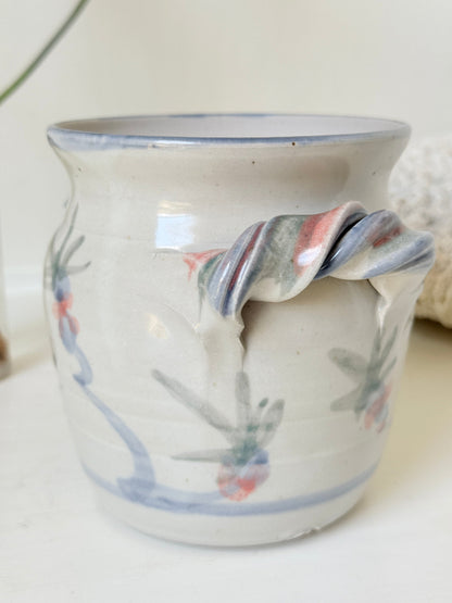 Vintage studio pottery utensil pot with hand painted floral decoration and applied handle detail, photographed on a white surface