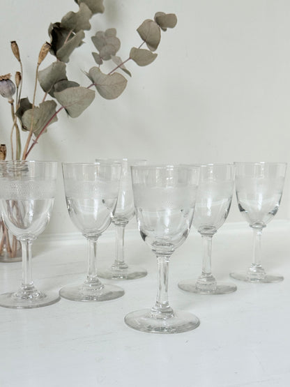 Set of six vintage etched clear glasses with decorative banding, one with a tiny rim chip, photographed on white surface.