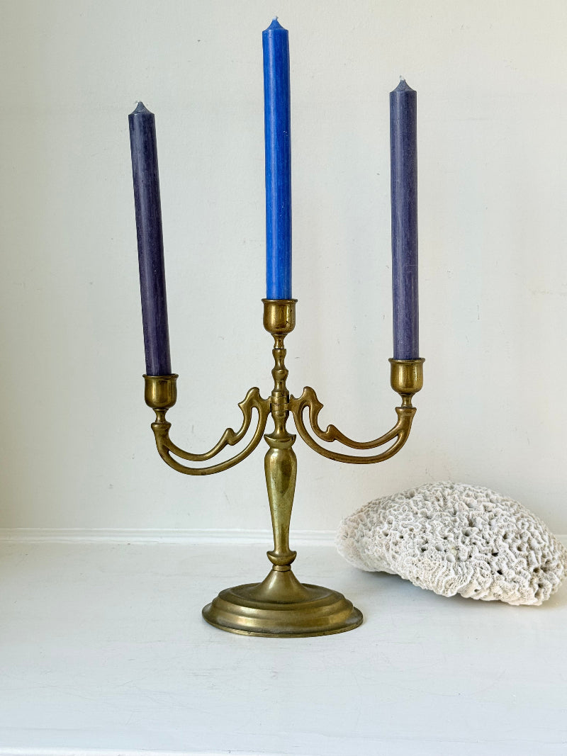 Vintage brass three-arm candelabra with curved arms and soft patina, photographed on a white surface