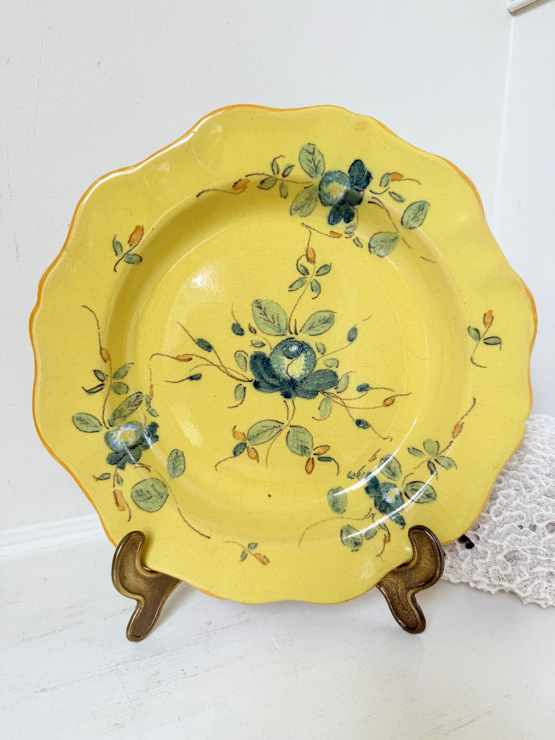 Vintage yellow French faïence plate with scalloped edge and blue floral decoration, photographed on a white surface