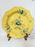 Vintage yellow French faïence plate with scalloped edge and blue floral decoration, photographed on a white surface