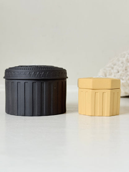Pair of vintage Wedgwood Jasperware trinket pots in black and yellow with white relief decoration, photographed on a white surface