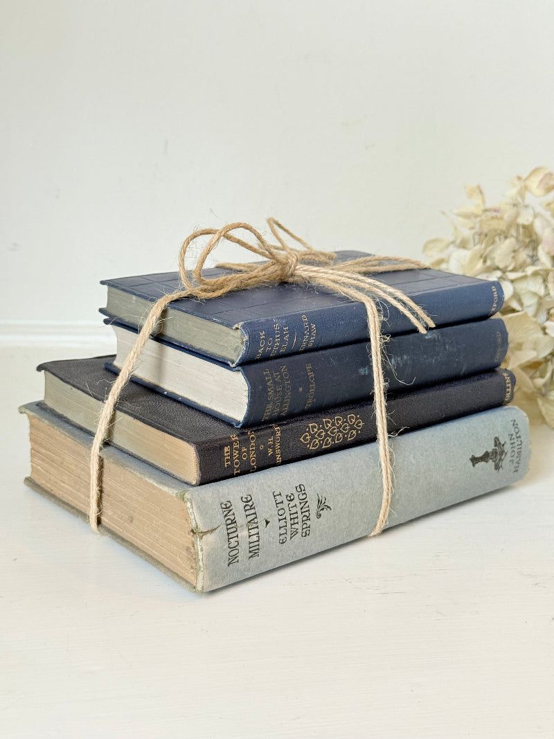 Vintage decorative book bundle in navy, grey, and cream tied with twine, photographed on a white surface