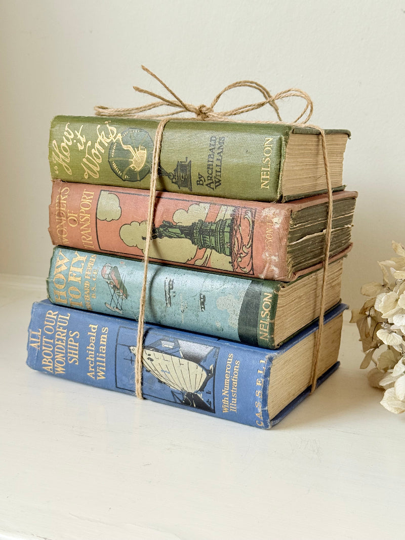 Vintage decorative book bundle in green, blue, and coral with printed lettering, tied with twine, photographed on a white surface