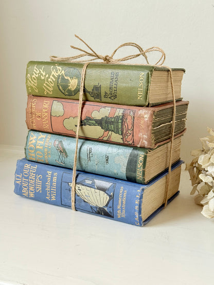 Vintage decorative book bundle in green, blue, and coral with printed lettering, tied with twine, photographed on a white surface