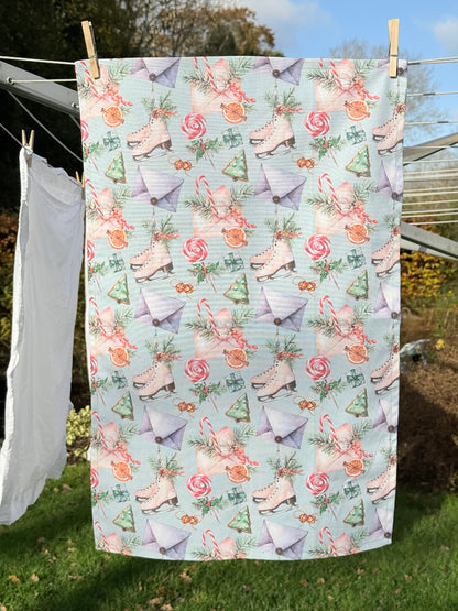 Blue Loft Christmas cotton tea towel with ice skate and candy pattern photographed on a white surface.