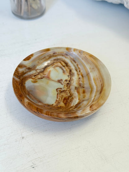 Vintage onyx marble soap dish in honey and cream with banded veining, photographed on a white surface