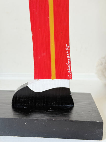 Vintage bellboy candlestick holder in red and black holding a tray with candle, photographed on a white surface