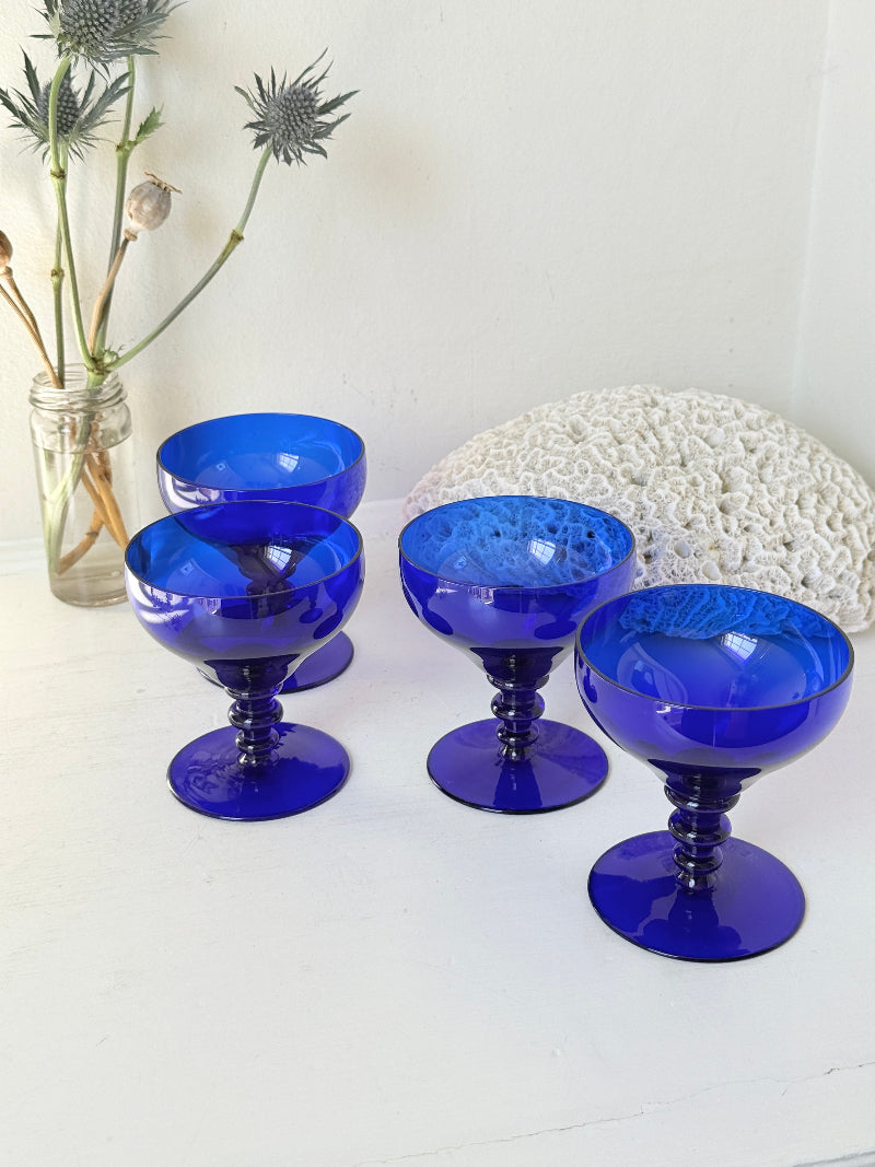 Set of four vintage cobalt blue cocktail glasses with stepped stems, photographed on a white surface