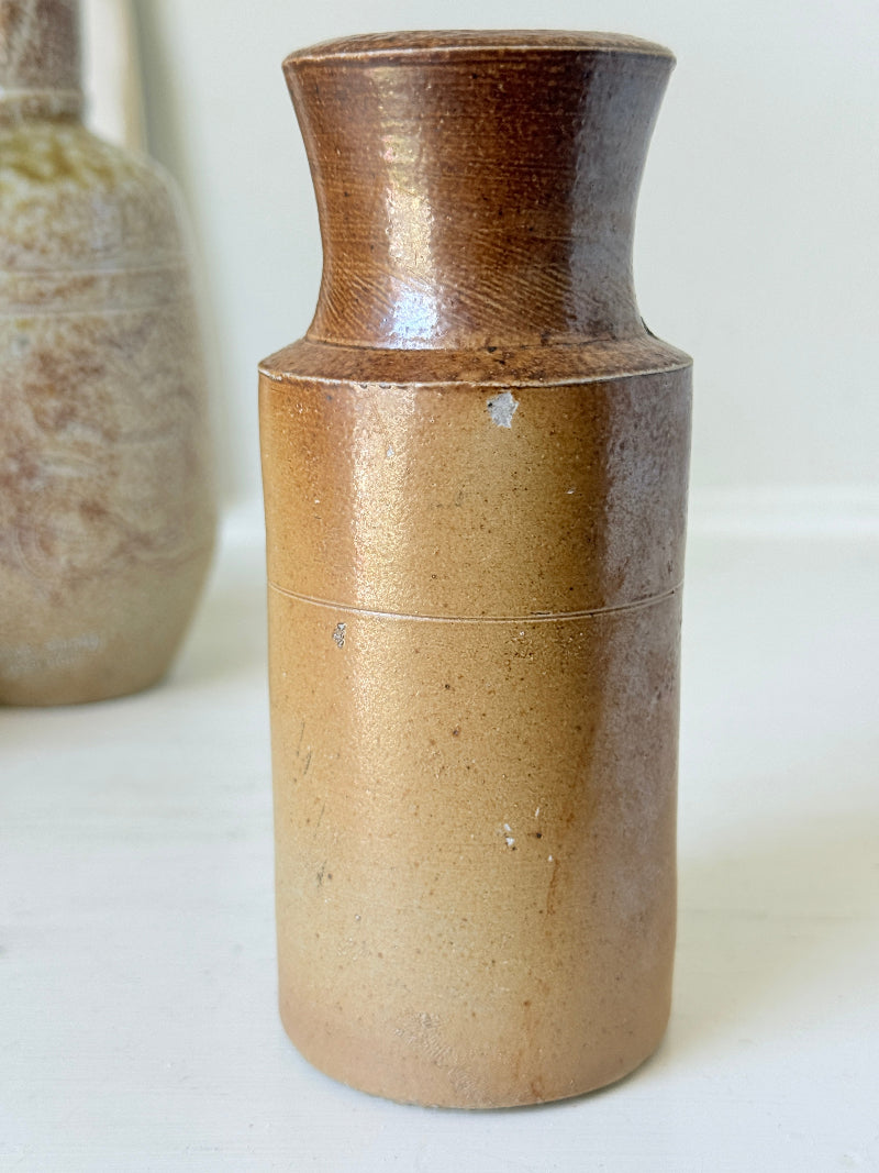 Three antique stoneware bottles, a printed Caley of Norwich and a Portuguese Campos Filhos, photographed on a white surface