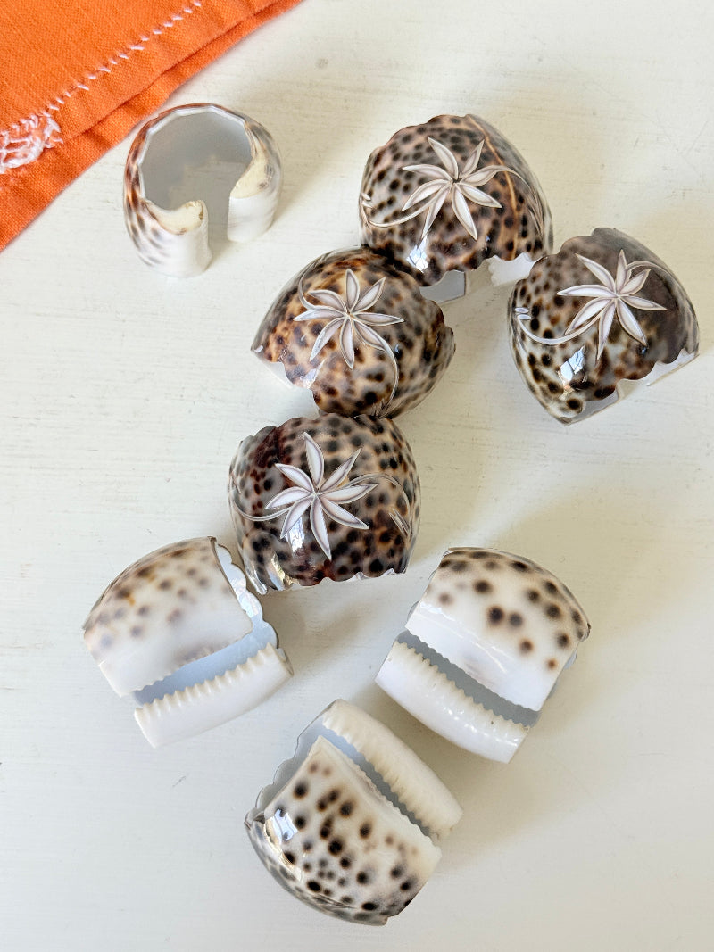 Set of eight vintage shell napkin rings with natural speckled patterning, photographed on a white surface