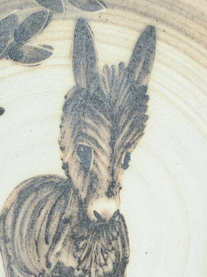 Vintage plate with hand painted brown donkey illustration and dark rim, photographed on a white surface