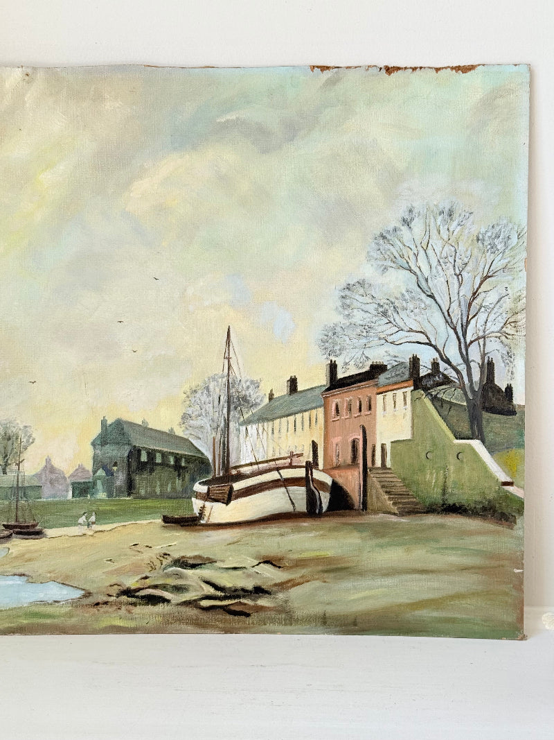 Vintage oil painting on board of a rural village scene with houses, trees, and water, photographed on a white surface