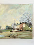 Vintage oil painting on board of a rural village scene with houses, trees, and water, photographed on a white surface