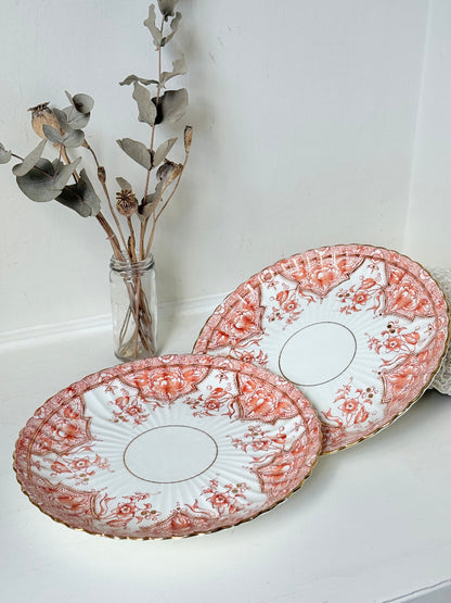 pair of vintage porcelain coral transfer plates with scalloped edges and gilt detail on white surface