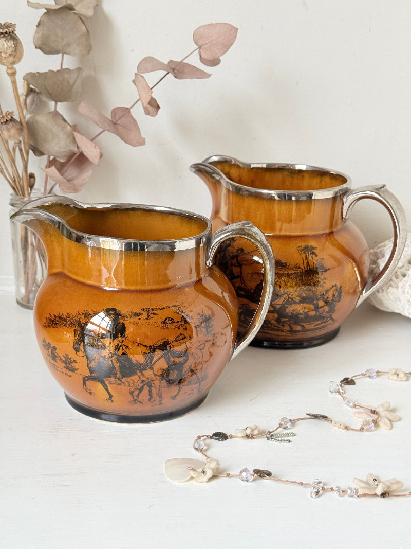 Pair of vintage Ridgways Coaching Days and Coaching Ways treacle jugs in amber brown glaze photographed on a white surface