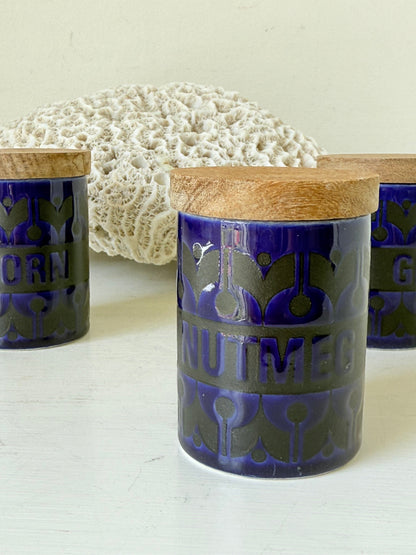 Set of three Hornsea Pottery spice jars in cobalt blue with wooden lids, labelled Ginger, Nutmeg, and Peppercorn, photographed on white surface

