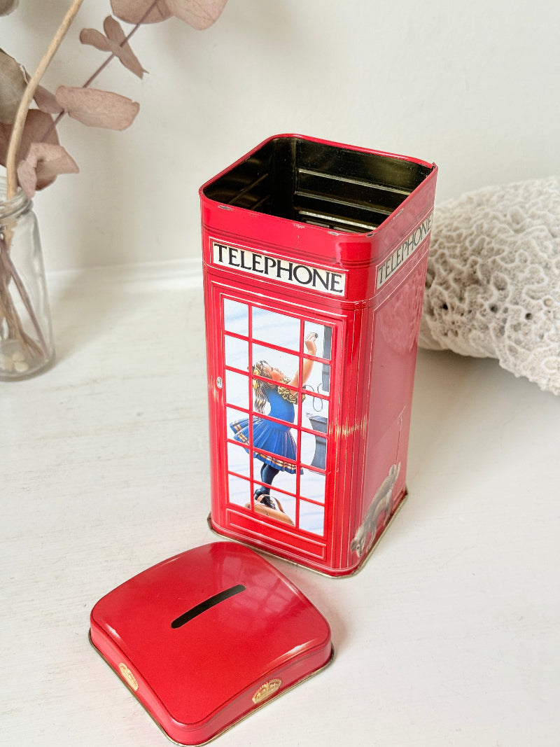 Vintage red telephone box tin money box on a white surface