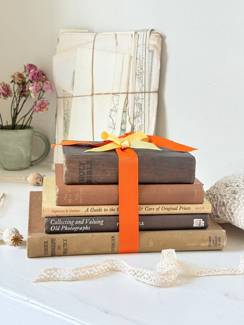 Vintage decorative book bundle in orange and brown with aged hardback covers and bright orange ribbon for shelf styling