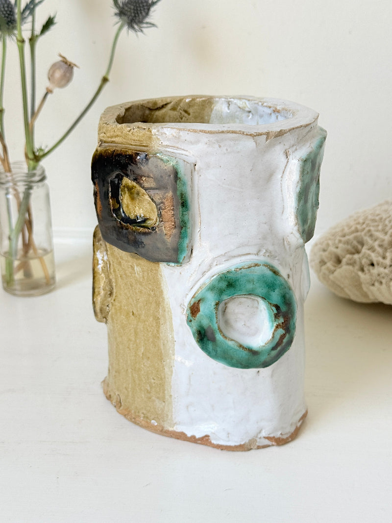 Vintage studio pottery vase in white, ochre and turquoise with abstract applied decoration, photographed on a white surface