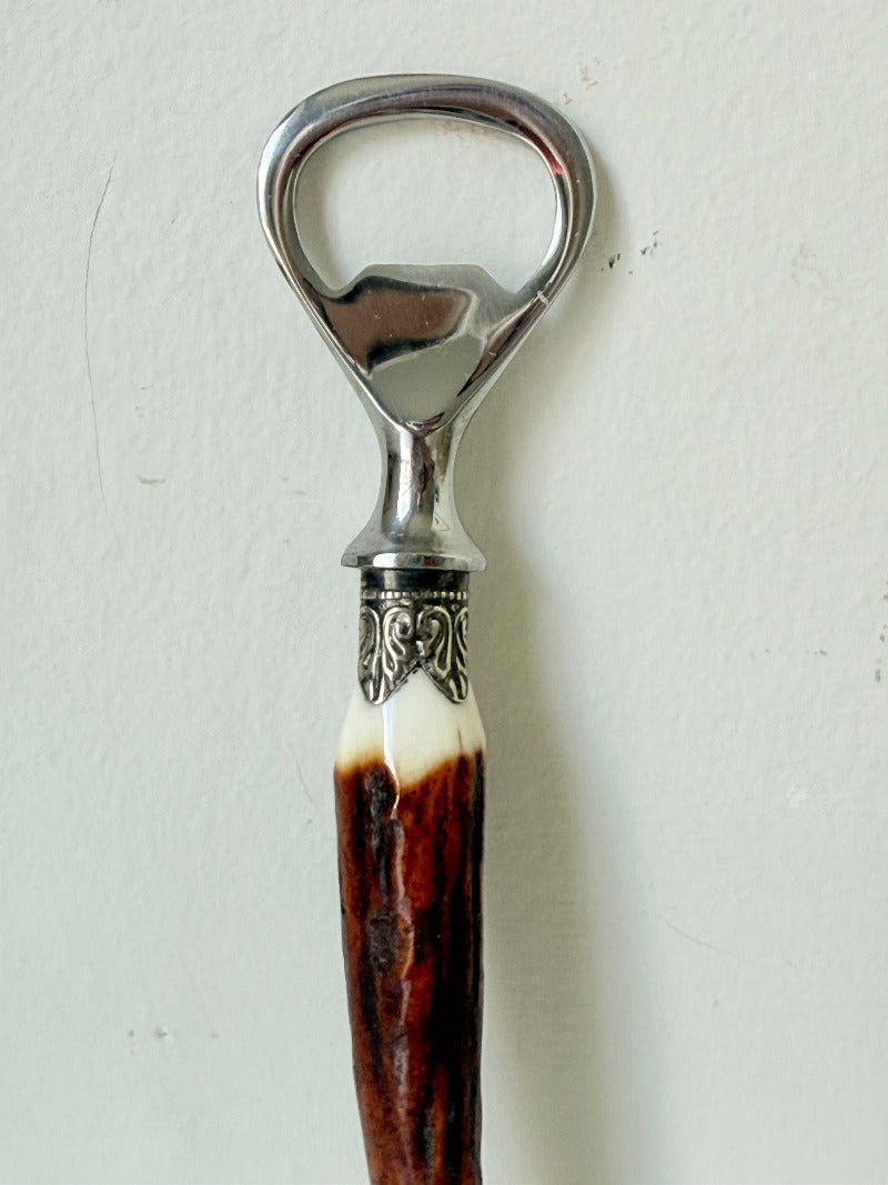 vintage antler handle bottle opener with stainless steel top photographed on white surface