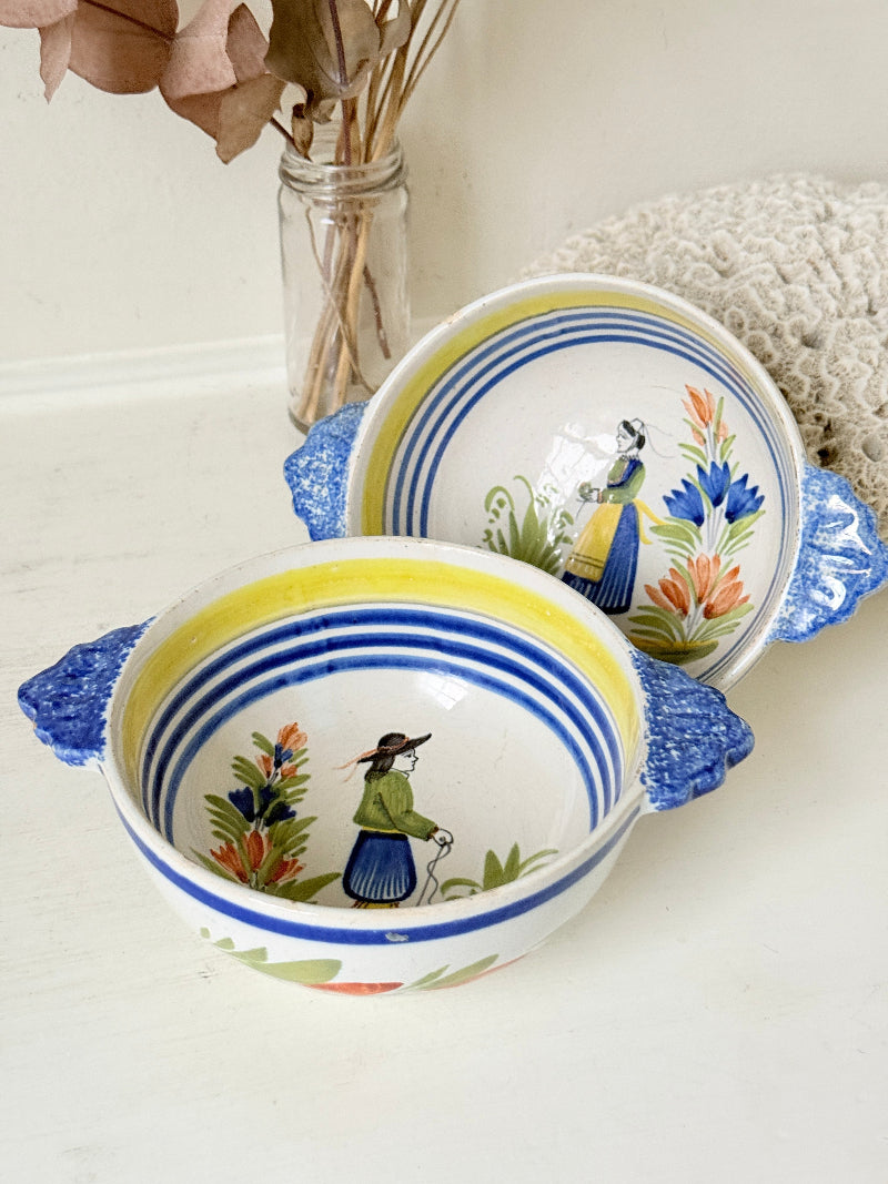 Pair of vintage French Quimper Breton figure bowls with blue handles, photographed on a white surface