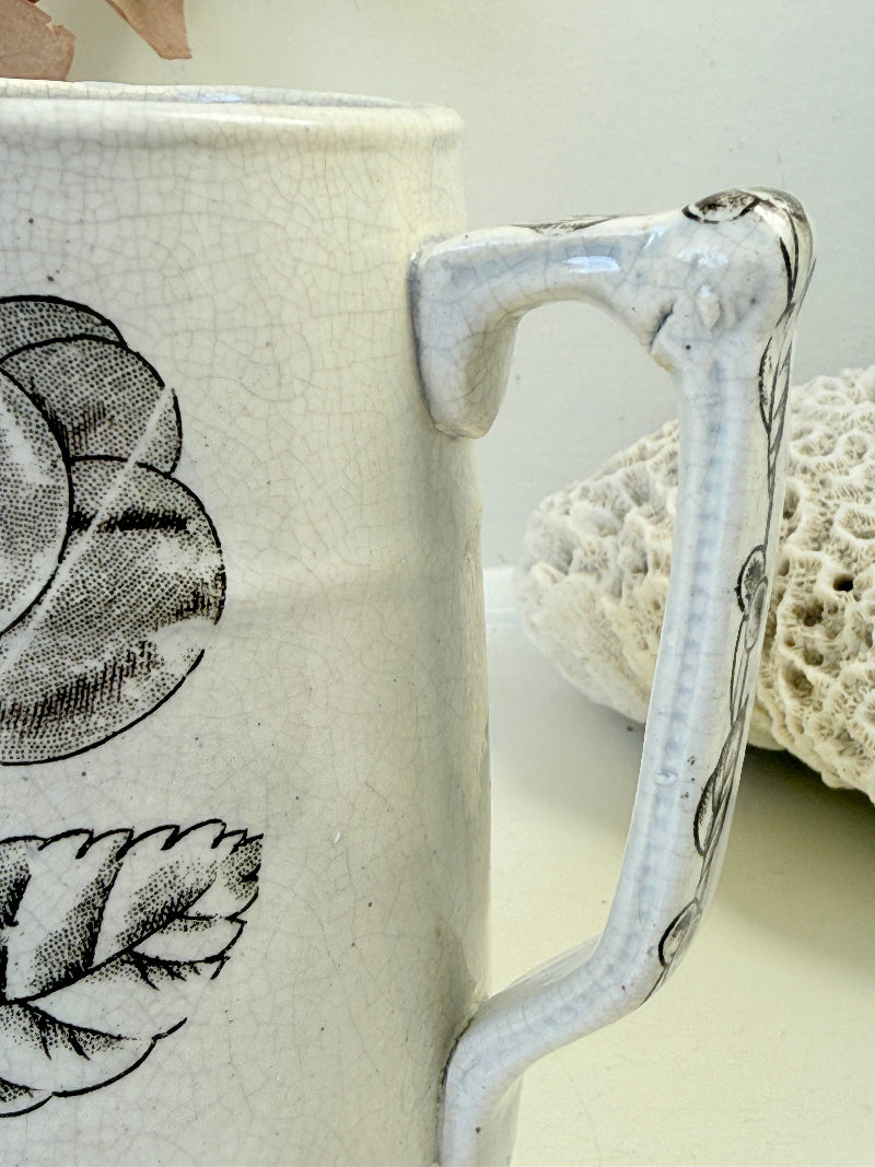 Antique English transferware jug with black fruit and leaf design, photographed on a white surface