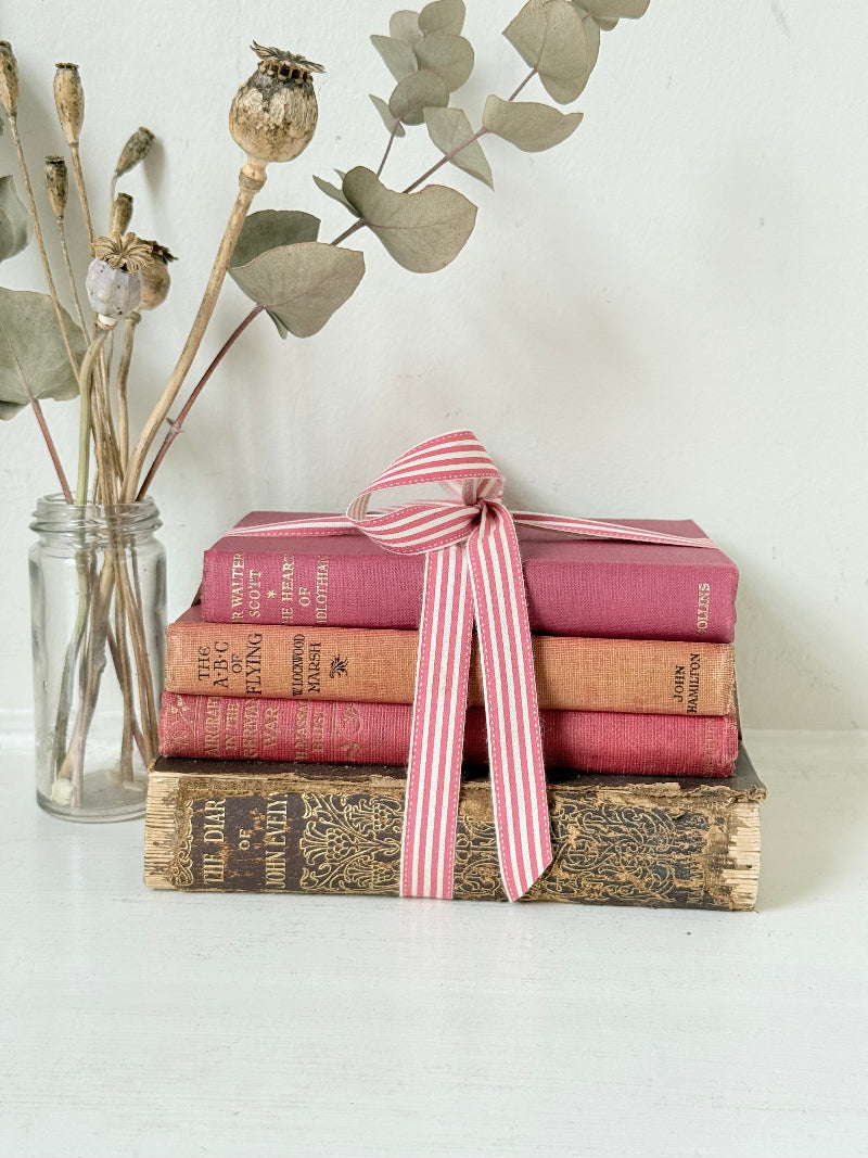 Vintage autumn colours decorative book bundle with pink ribbon, photographed on a white surface