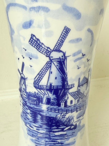 Blue and white Delft hand painted ceramic vase with windmill and floral decoration, photographed on white surface.