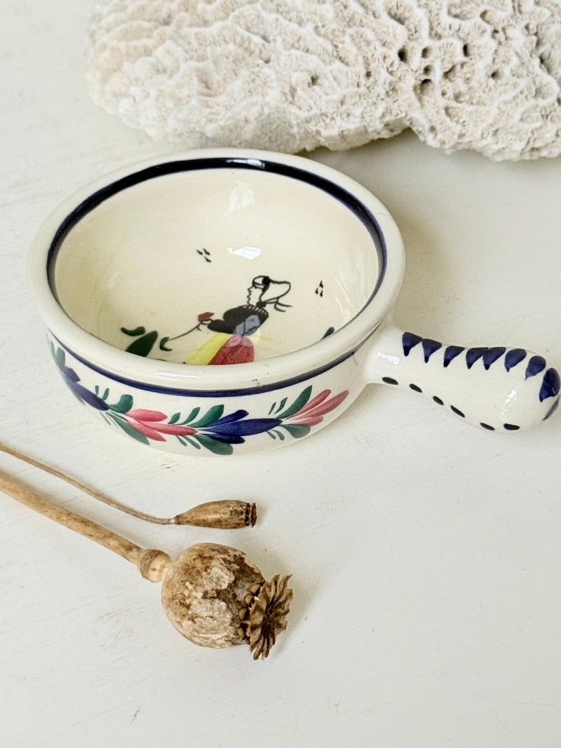 French Quimper faience handled olive bowl with Petit Breton figure and blue rim, photographed on a white surface