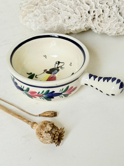 French Quimper faience handled olive bowl with Petit Breton figure and blue rim, photographed on a white surface