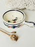 French Quimper faience handled olive bowl with Petit Breton figure and blue rim, photographed on a white surface