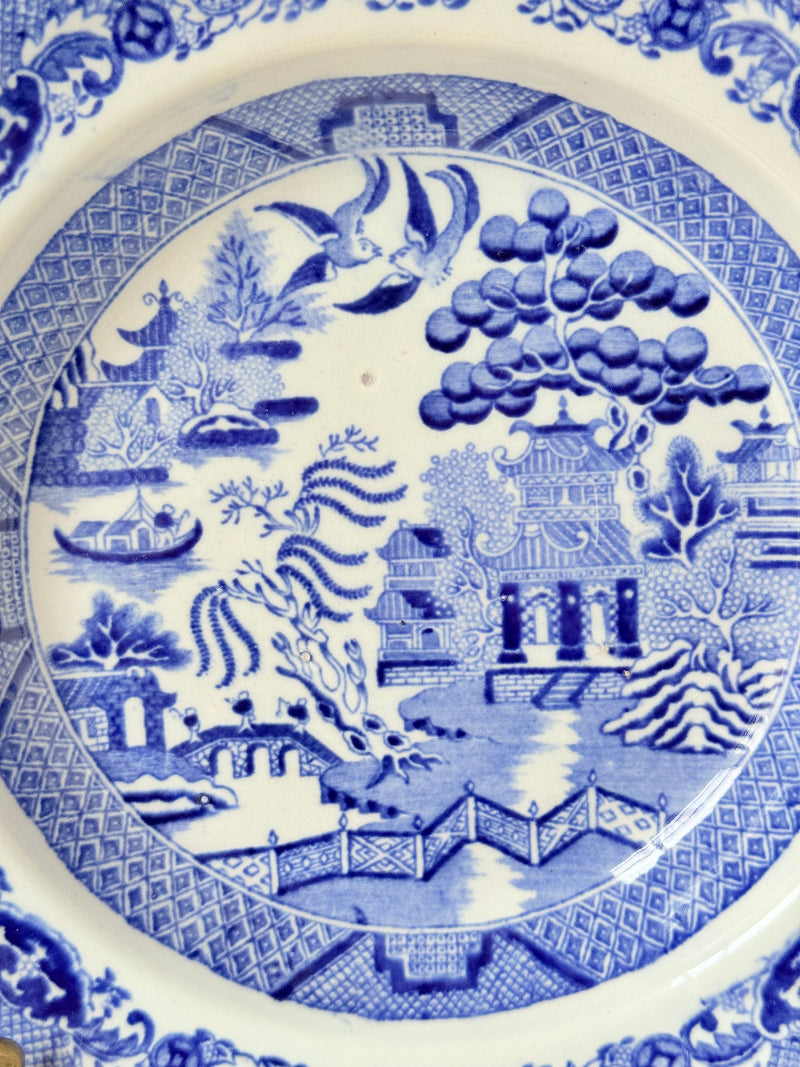 Antique Blue Willow serving bowl with cobalt transfer pattern shown on a white surface.