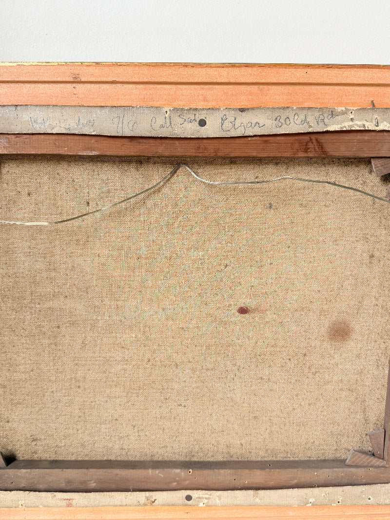 The back of a framed canvas or painting showing the tan linen fabric backing, wooden frame, wire support, and handwritten inscription near the top.