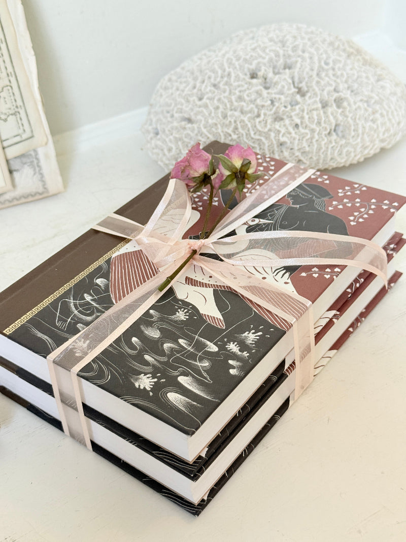 Pair of vintage Greek myths books with brown illustrated covers, pale pink ribbon and dried flower detail for shelf styling