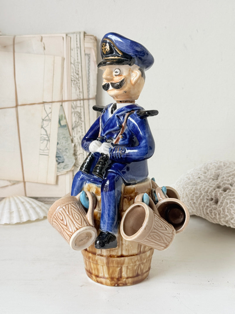 Vintage figural ceramic decanter set with captain, navy blue uniform, barrel base and 6 matching barrel shot cups