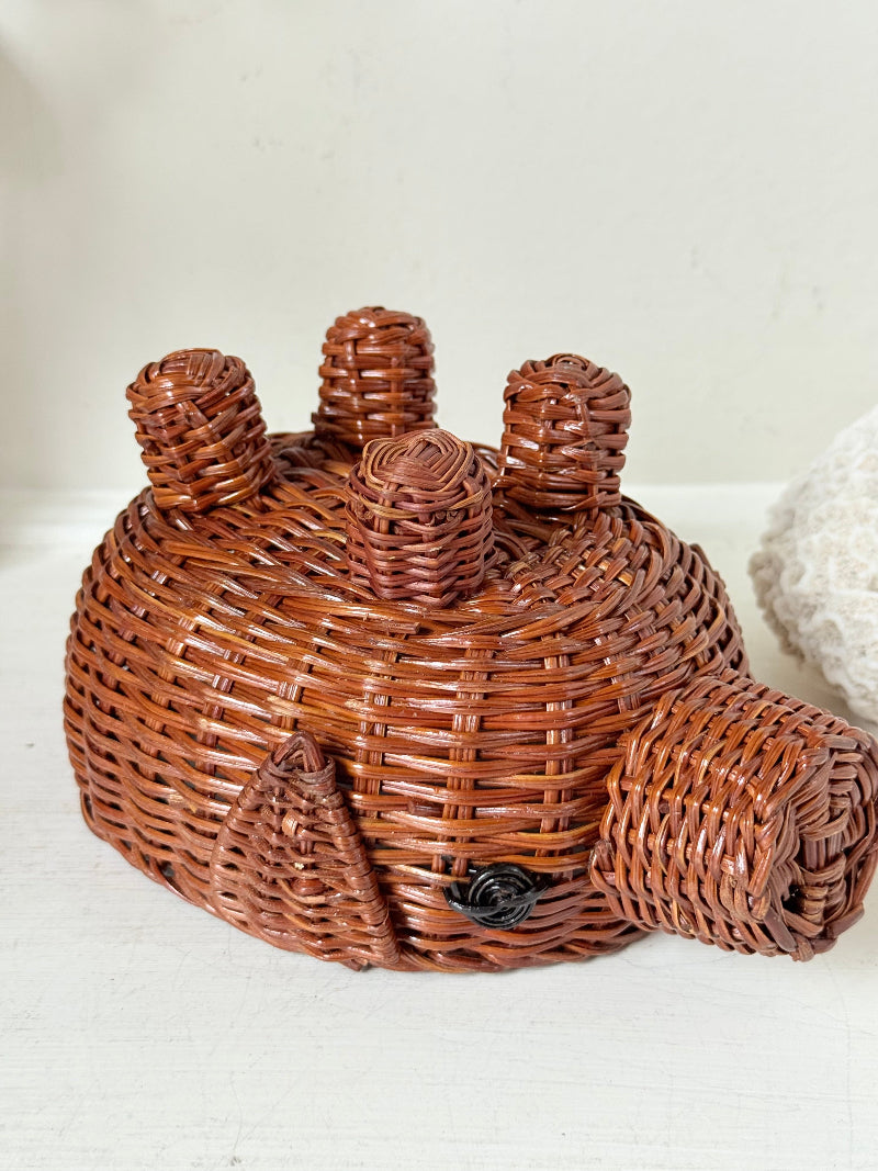 Vintage wicker pig basket planter in warm brown, photographed on a white surface
