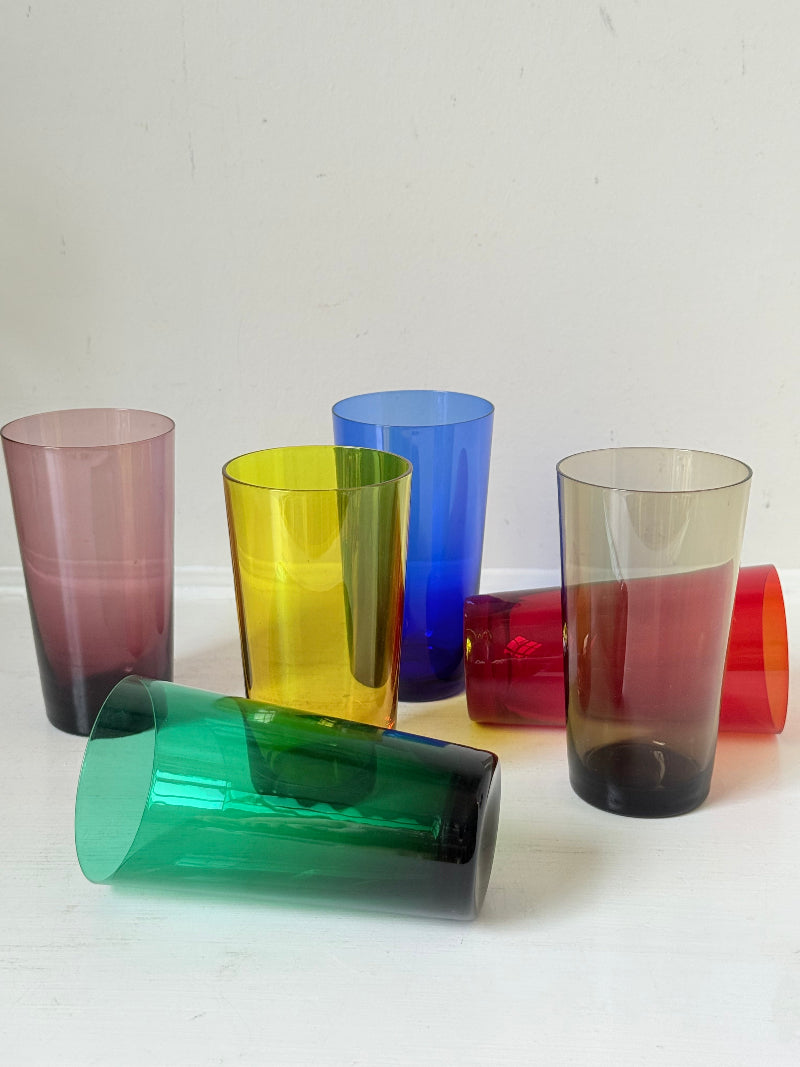 Set of six mid-20th century Boussu coloured glass tumblers in green, yellow, red, violet, blue and brown, photographed on white surface.
