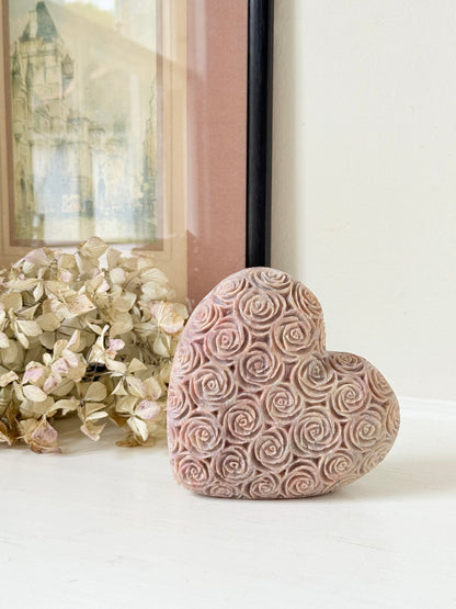 vintage pink stone heart with engraved roses and flat base on white surface