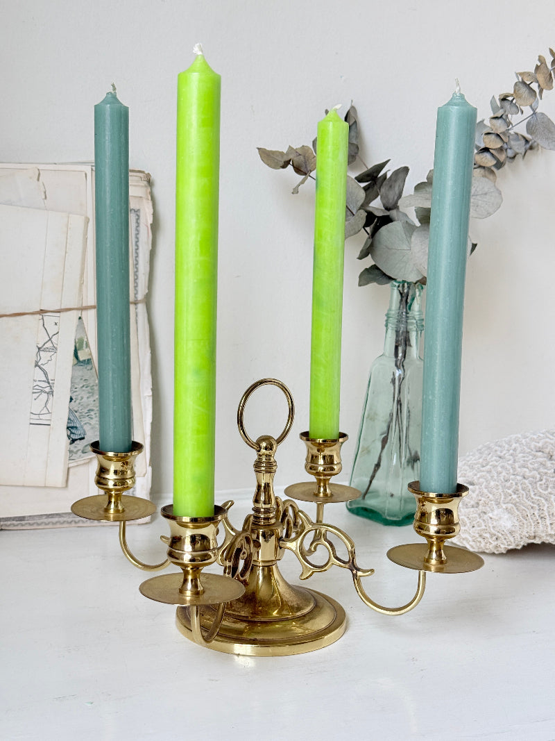 Brass five light candelabra with scrolled arms and a central ring handle on a domed base, photographed on a white surface