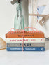A stack of four vintage Warne aviation reference books tied with red-and-white string, placed on a white surface with a glass bottle and nautical decor in the background.