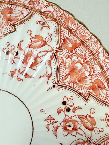 pair of vintage porcelain coral transfer plates with scalloped edges and gilt detail on white surface