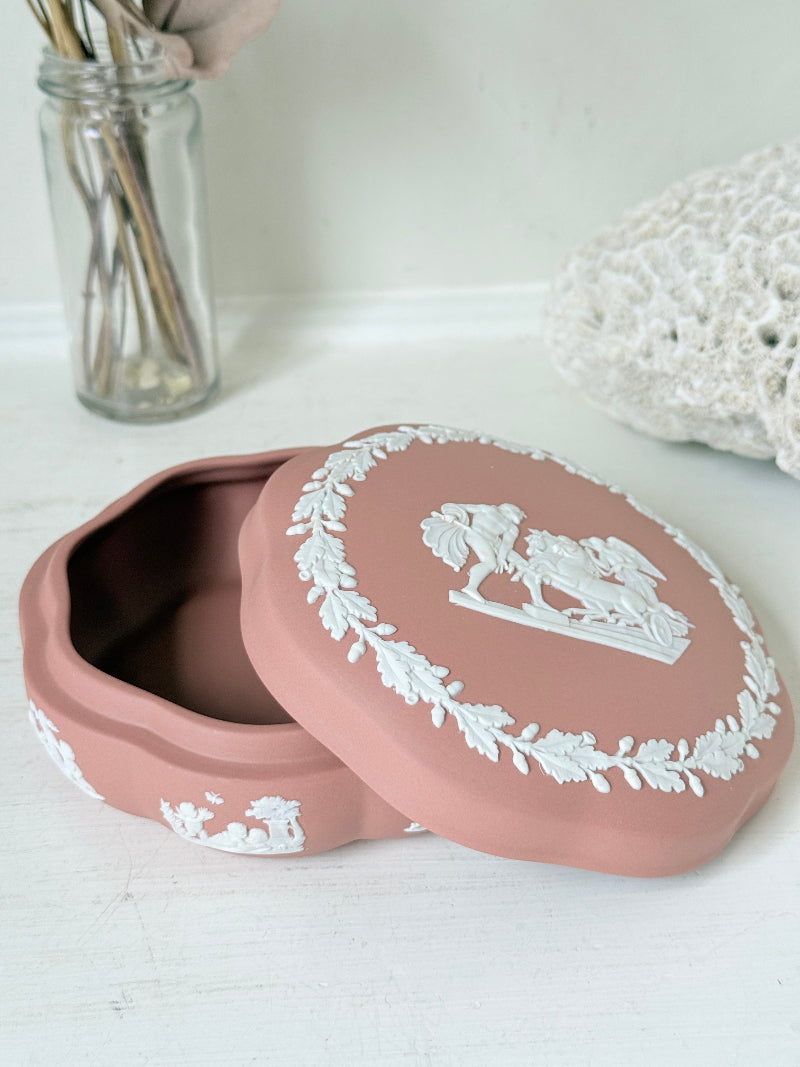 Rare vintage Wedgwood Jasperware round lidded trinket box in terracotta rose pink, with a central classical cameo scene and white laurel wreath border.
