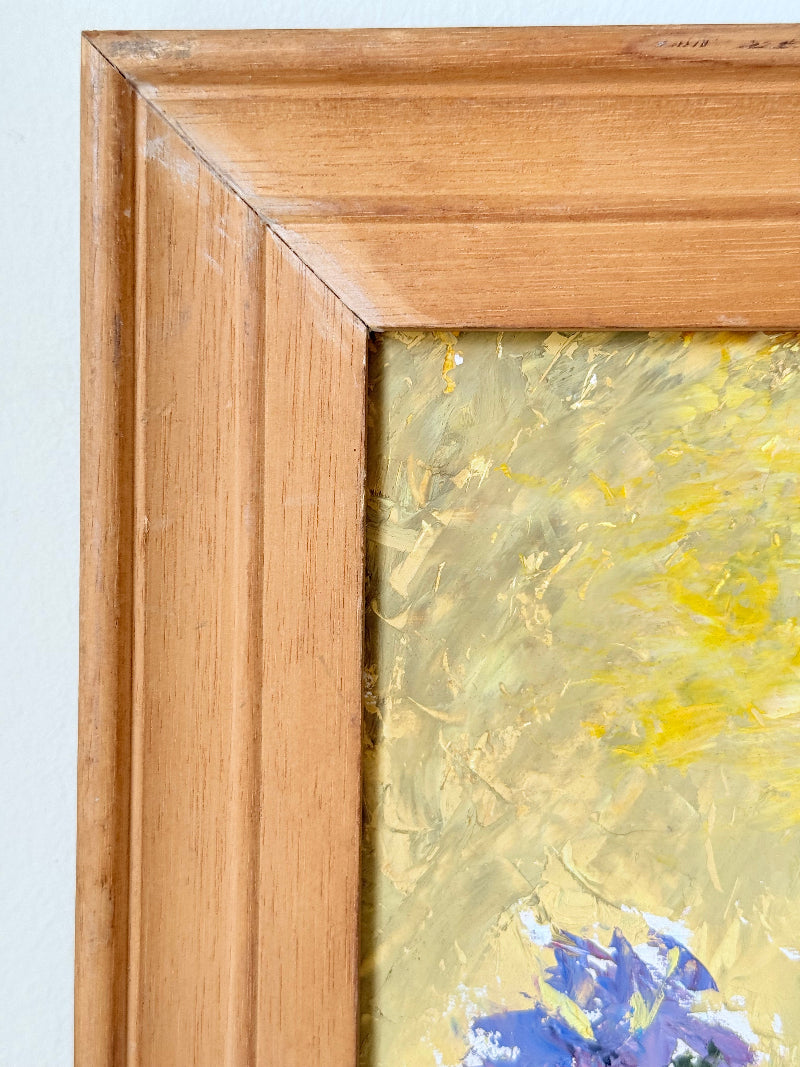 Vintage oil painting of cornflowers in a vase with yellow background in wooden frame photographed on a white surface