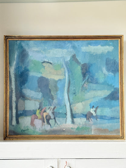 An impressionist-style landscape painting in a gold frame, hanging on a beige wall above a white cabinet. The painting depicts figures on horseback in a blue-toned forest scene.
