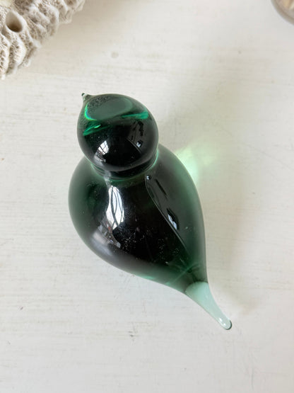Vintage green glass bird paperweight photographed on a white surface