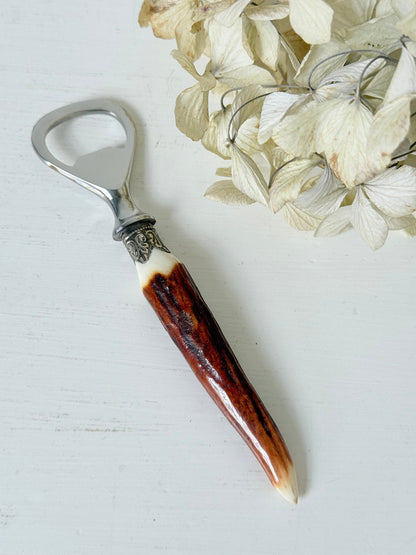 vintage antler handle bottle opener with stainless steel top photographed on white surface
