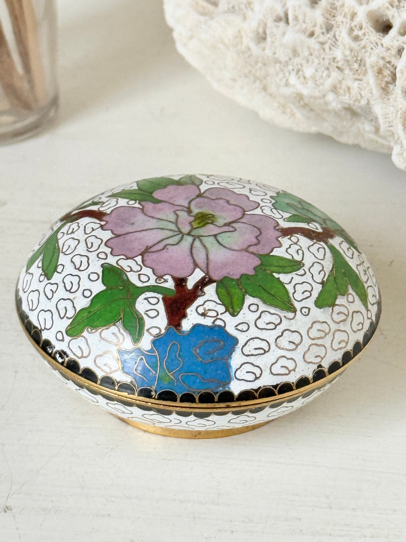 Vintage brass and enamel cloisonne trinket box with floral lid and turquoise interior photographed on a white surface